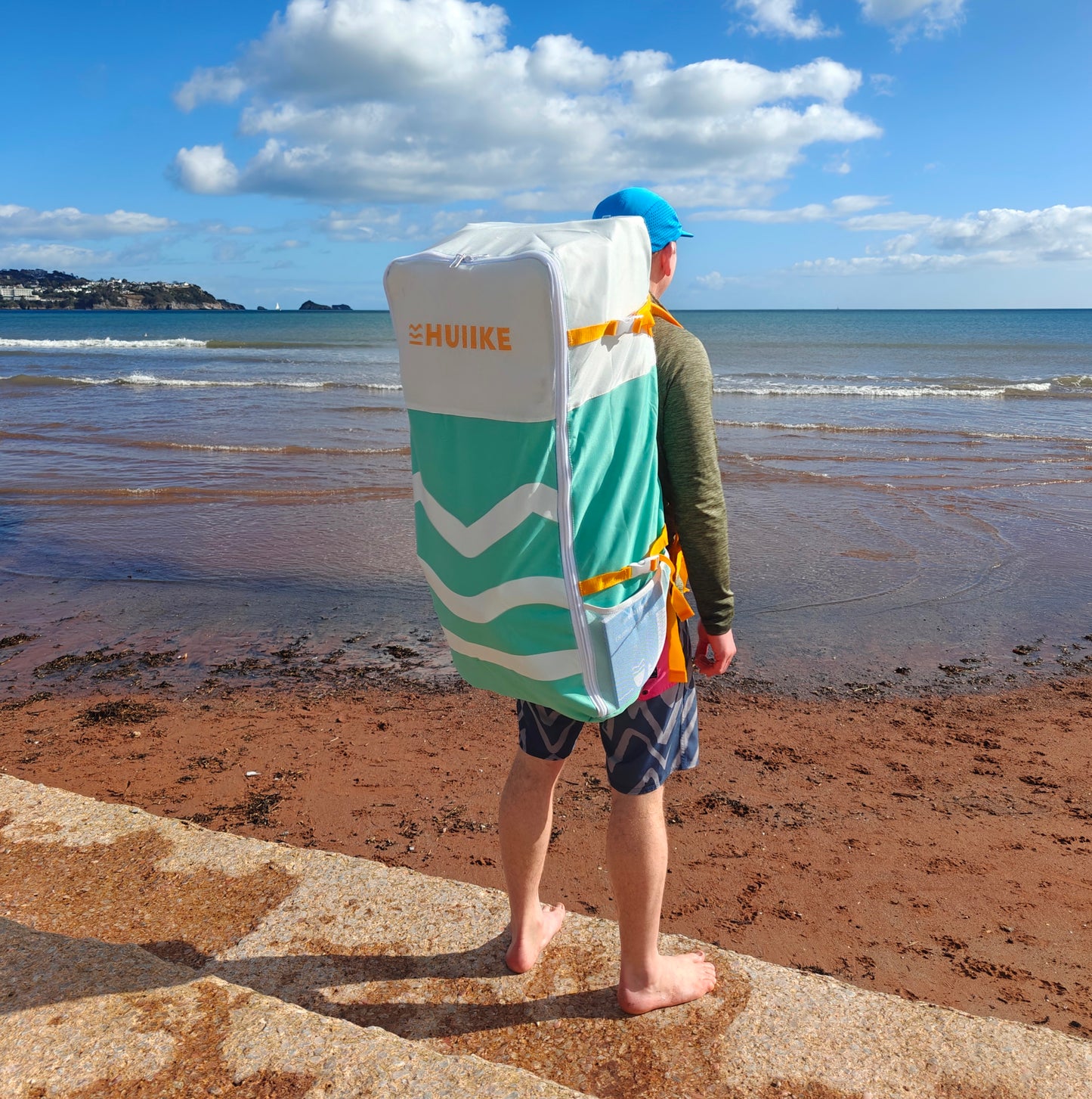 Person with a green and white SUP backpack on a beach